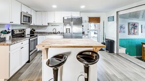 A modern kitchen with white cabinets, stainless steel appliances, and a wooden island with two bar stools. - 2 Mi to Beach! Canal-front Escape in Crystal River (Crystal River)