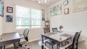 A dining area with a large table, chairs, and a chandelier. There are windows with blinds, artwork on the walls, and a clock. - Pets Welcome! Family Townhome w/ Yard in Atlanta (Atlanta)