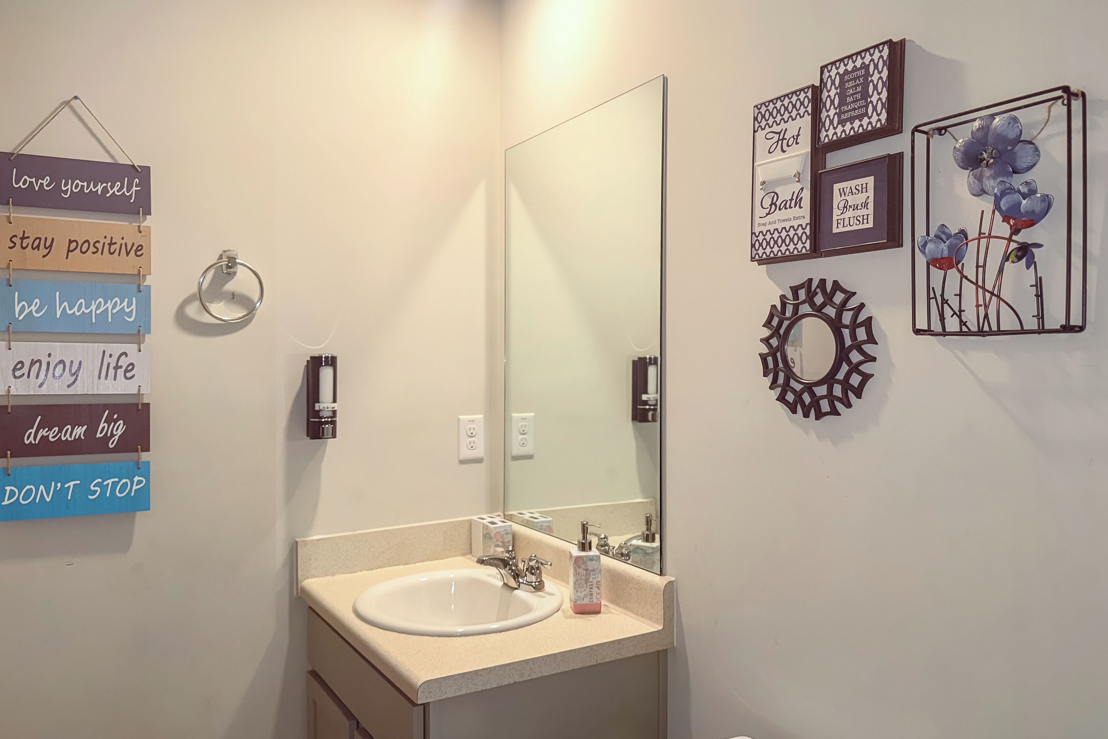A bathroom with a sink, mirror, and motivational wall art.