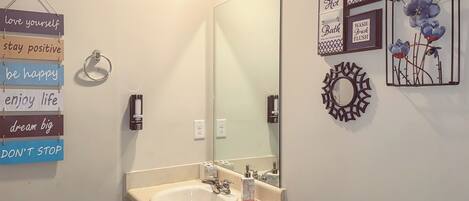 A bathroom with a sink, mirror, and motivational wall art.