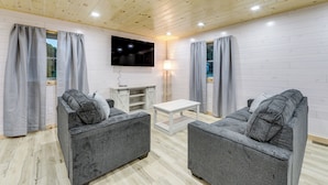 A cozy room with two grey sofas, a white TV stand, and a small white table. - Direct Trail Access: Lyons Falls Getaway w/ Views! (Lyons Falls)