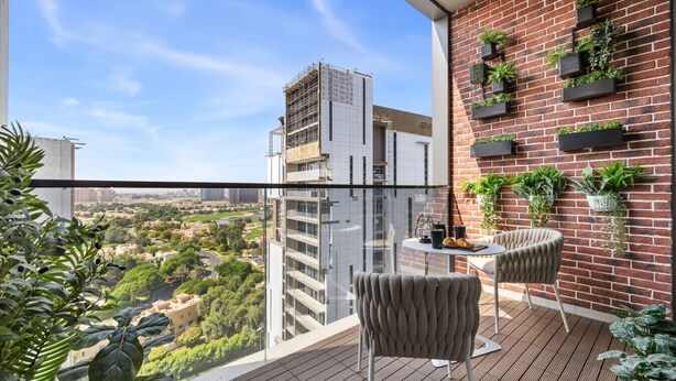 A balcony with a view of a cityscape, a brick wall with planters, and two chairs. - New 1BR with Rooftop Pool & Amazing View (Dubai)