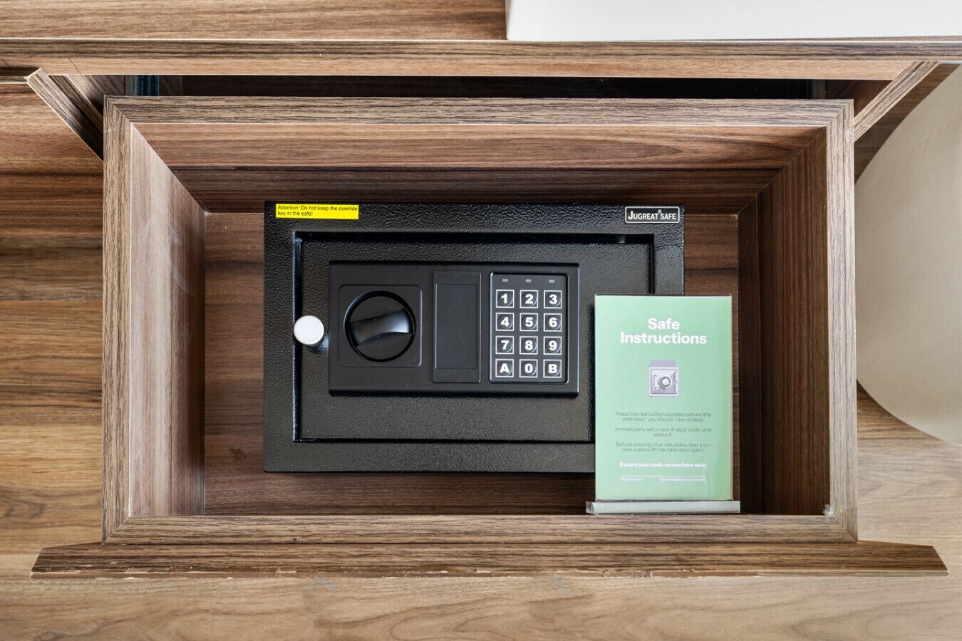 A safe deposit box with a keypad and a safe key, and a safe instructions booklet.