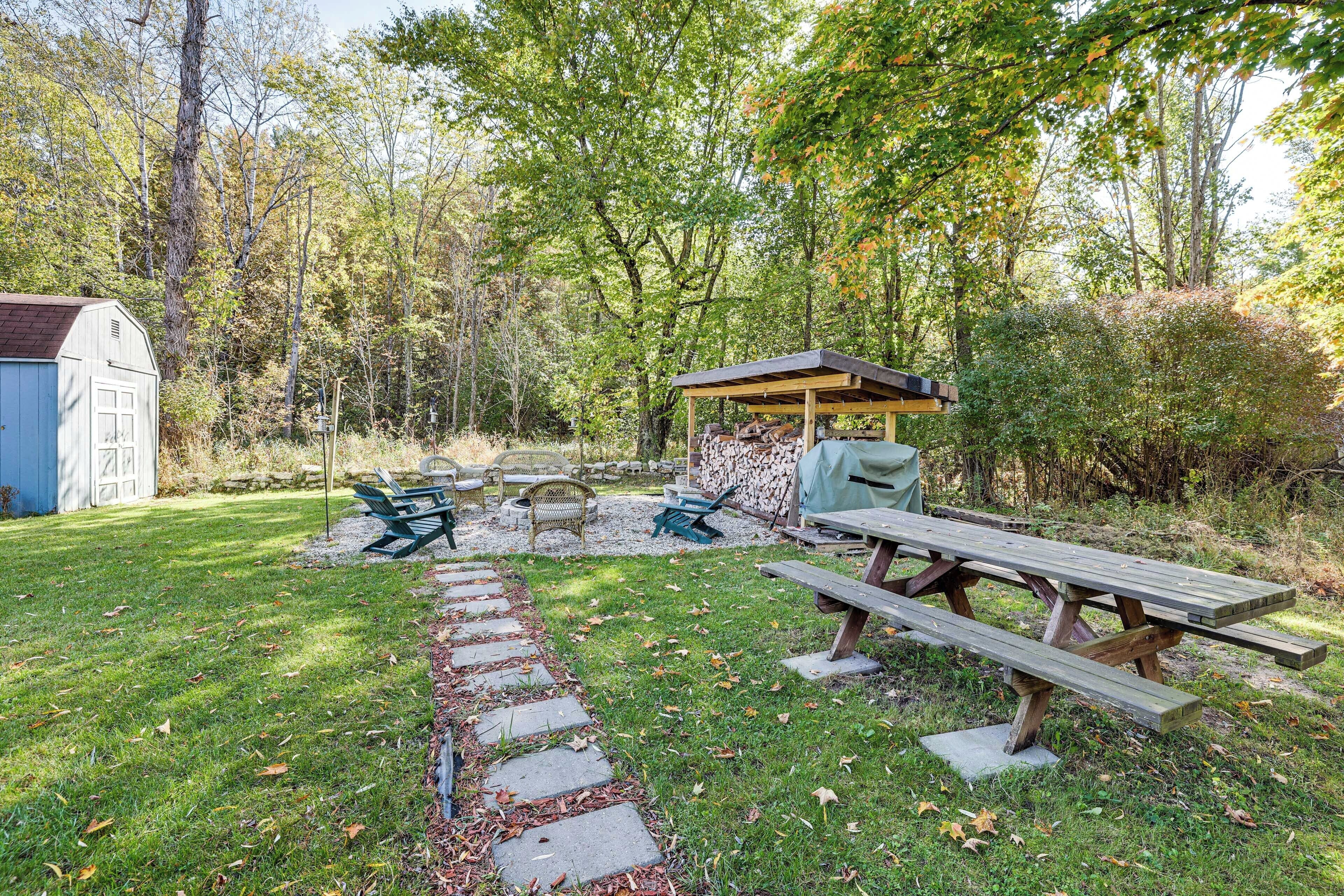 A backyard with a wooden picnic table, a covered seating area, and a shed.