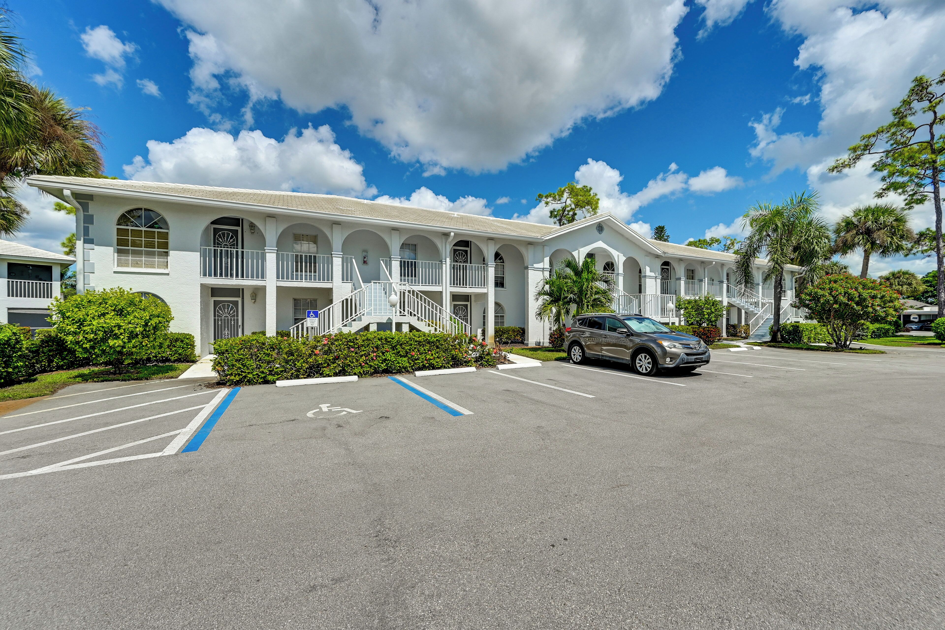 A white motel with multiple balconies and a parking lot.
