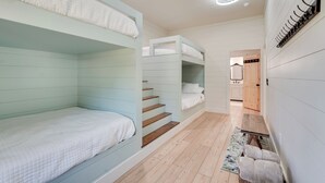 Ein Zimmer mit Etagenbetten, einer Holztreppe, einer Bank und einem Kleiderhaken.