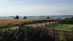 Vue d’une propriété située au bord de l’eau, avec une pelouse, une clôture en bois et un ciel dégagé.