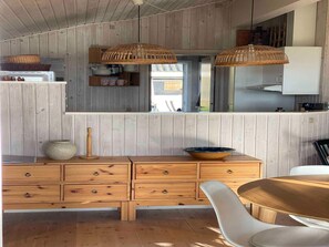A wooden-paneled kitchen with a wooden dining table and chairs, a white cabinet, and a hanging light fixture. - 5 Star Holiday Home in Faaborg (Faaborg)