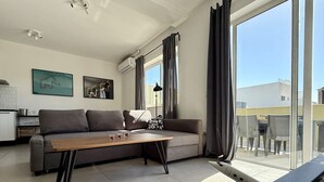 Ett modernt vardagsrum med en soffa, ett soffbord och stora fönster.