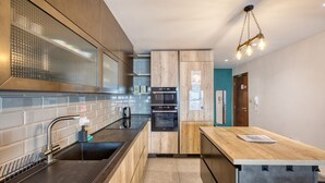 Una cocina moderna con un lavamanos de acero inoxidable, armarios de madera, horno empotrado y encimera de madera.