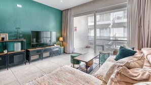 Una sala de estar moderna con una pared de acento color turquesa, un televisor de pantalla plana, una mesa de centro y un sofá.