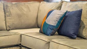 A beige sofa with a colorful cushion in an interior space with a brick wall and graffiti. - Luxury 2 Bedroom & 2 Bathroom Central Flat (Swansea)