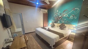 A bedroom with a bed, a desk, a chair, a ceiling fan, and a wall with a decorative design. - Paradise peak (Maafushi)
