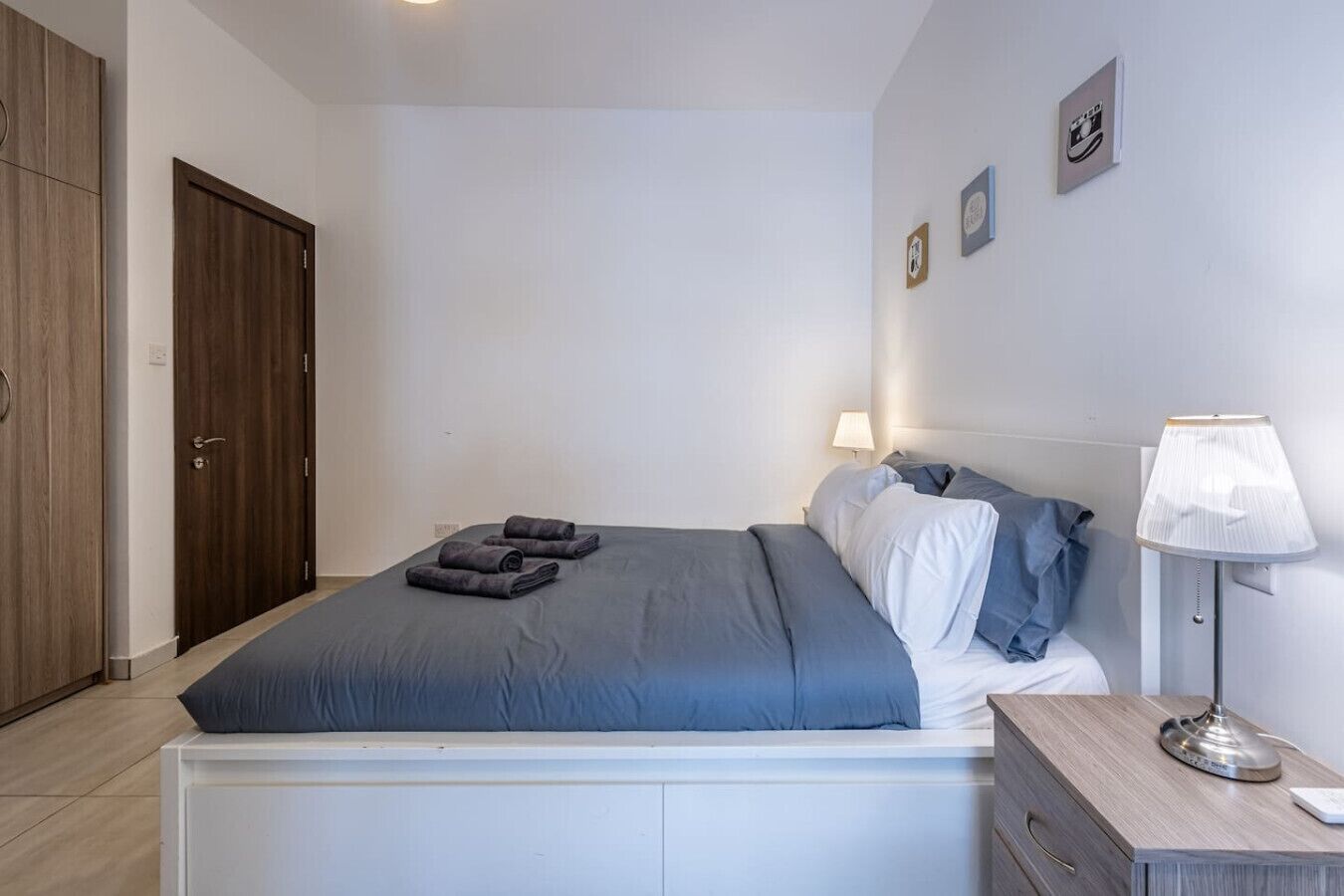 A bedroom with a bed, bedside table, lamp, and a wardrobe.
