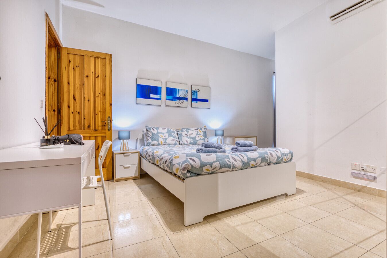 Ein Schlafzimmer mit Bett, Nachttischen, Schreibtisch und Kleiderschrank.