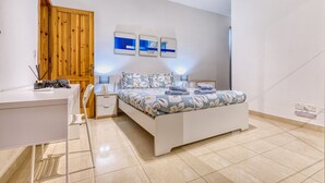 A bedroom with a bed, bedside tables, a desk, and a wardrobe. - The Beach Apartment - Sliema (Sliema)