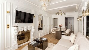 A luxurious living room with a large sofa, a fireplace, a television, and elegant decor. - Merveil Luxury Suite - Louvre Aboukir IX (Paris)