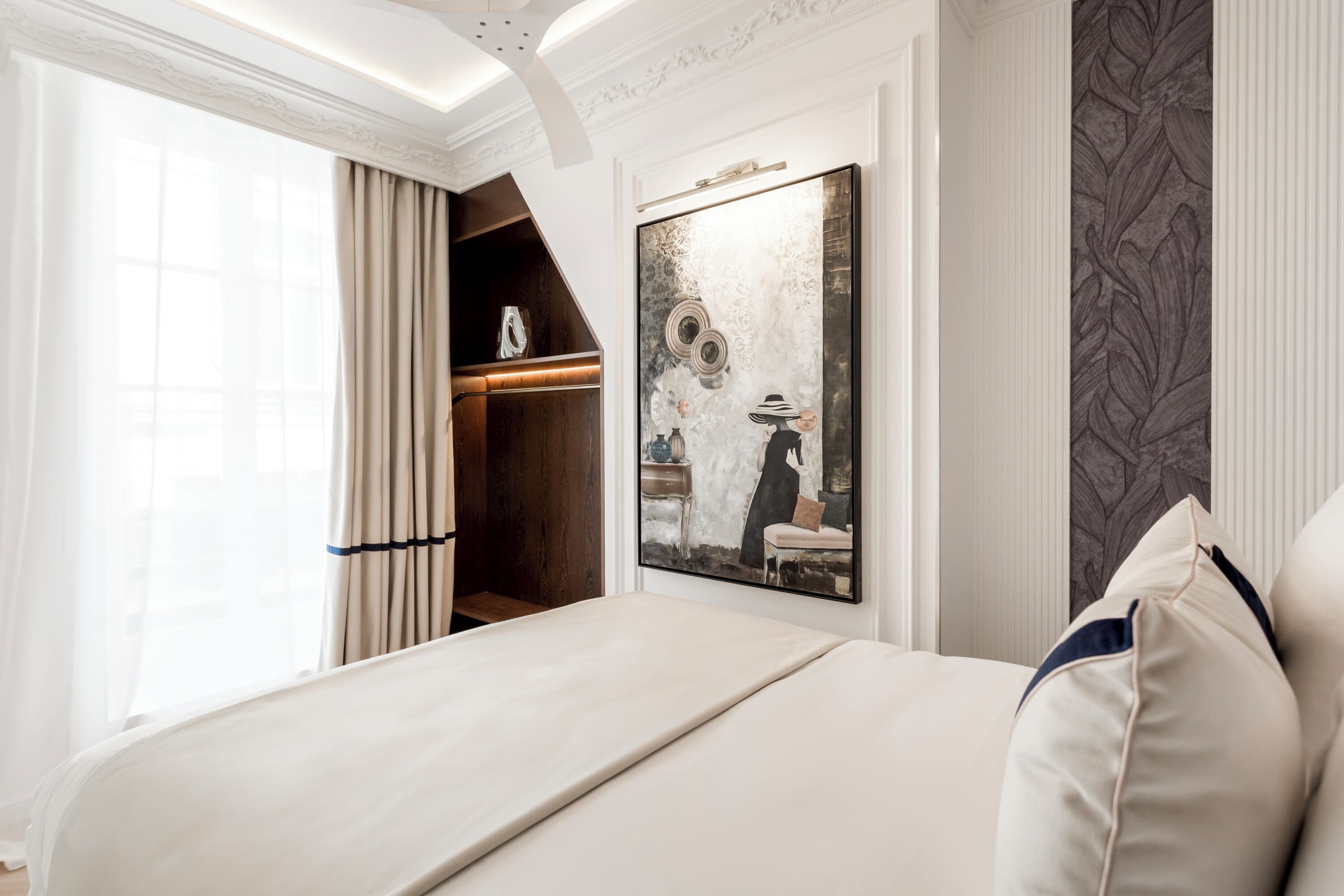 Habitación de hotel con una cama grande, un armario, un cuadro en la pared y vistas al exterior.