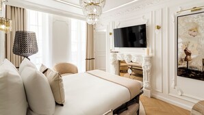 A luxurious bedroom with a large bed, a chandelier, a flat-screen TV, and a fireplace. - Merveil Luxury Suite - Louvre Aboukir IX (Paris)