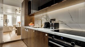 A modern kitchen with a marble countertop, black appliances, and wooden cabinets. - Merveil Luxury Suite - Louvre Aboukir IX (Paris)