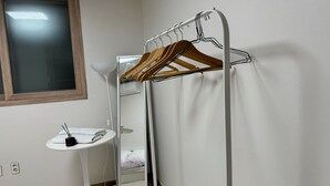Una camera d'albergo con uno stendino, un lavandino piccolo e uno specchio.