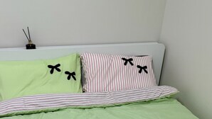 Un letto con una coperta a righe verdi e cuscini con fiocchi neri.