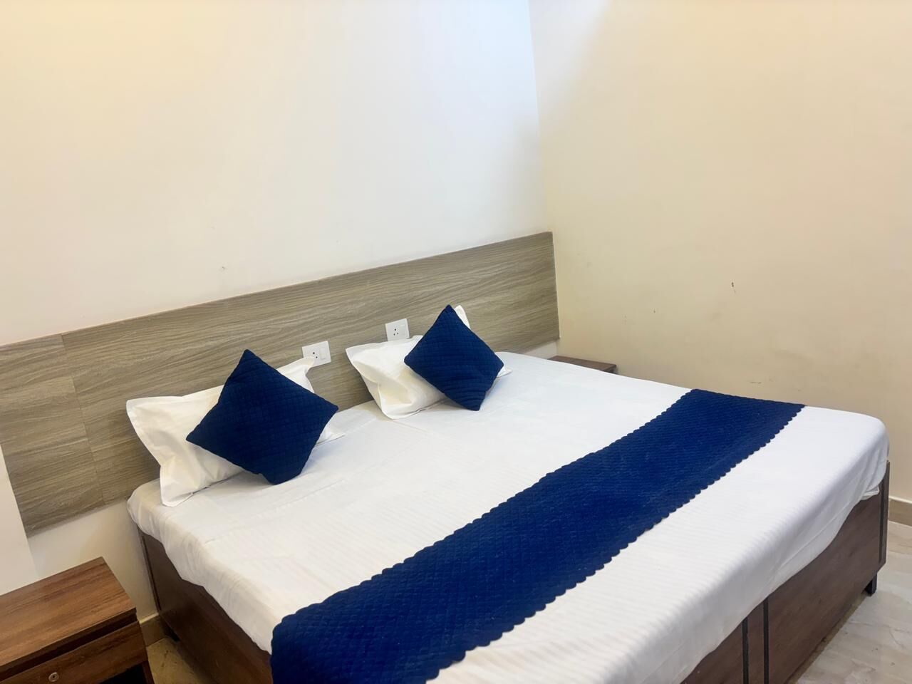Un lit bien fait, avec une couvre-lit blanche et bleue, deux oreillers et une tête de lit en bois.