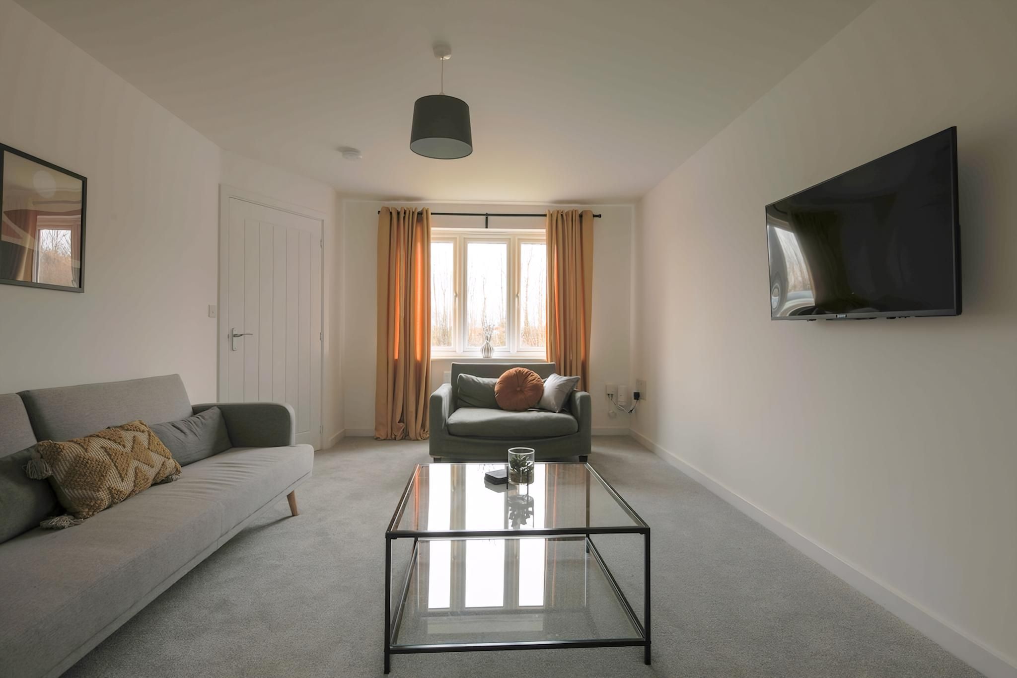 A modern living room with a sofa, a coffee table, a television, and a window with curtains.