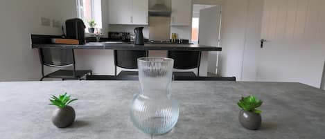 A modern kitchen with white cabinets, a black countertop, and a clear glass vase on the table.