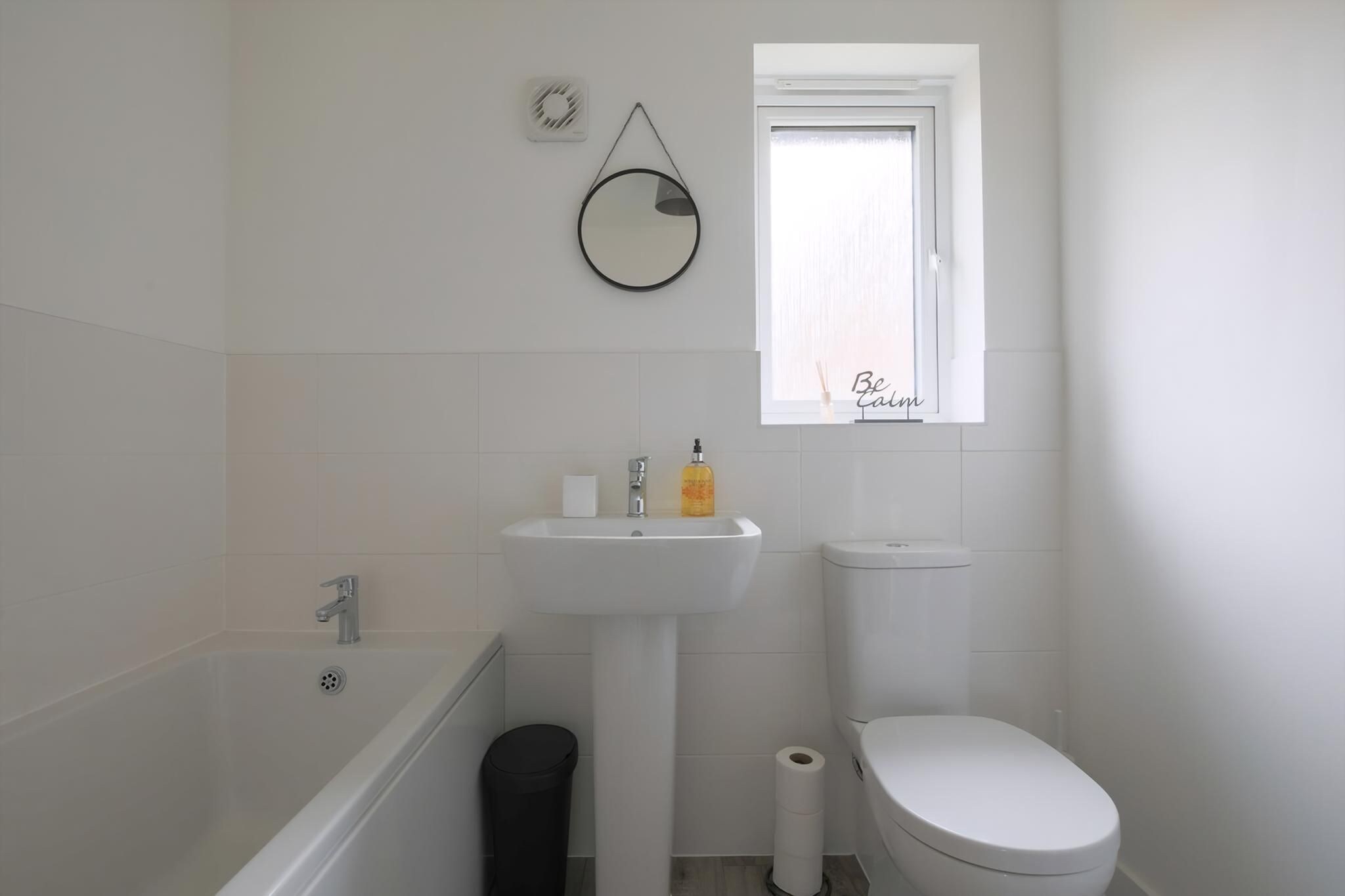 A bathroom with a bathtub, sink, toilet, and a window with a view.