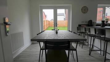 Una cocina moderna con una mesa de comedor, sillas, un reloj y vistas a un patio trasero.