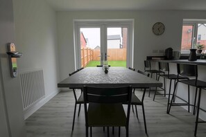 Une cuisine moderne avec une table à manger, des chaises, une horloge et une vue sur un jardin.