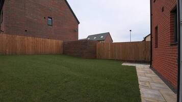 A brick building with a wooden fence and a well-maintained lawn.
