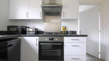 A modern kitchen with white cabinets, a black dishwasher, a microwave, an oven, and a gas stove.