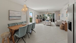 Un salon moderne comprenant un coin repas, une cuisine et donnant sur l’extérieur.