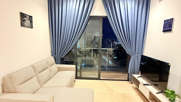 A modern living room with a beige sofa, a flat-screen TV, and a ceiling fan. - LUCENTIA RESIDENCE BY HORIZON HOME (Kuala Lumpur)