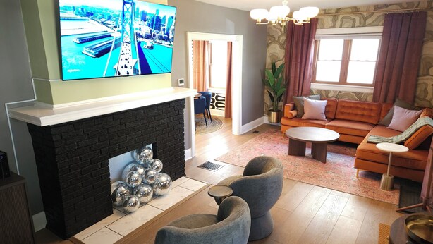 A living room with a fireplace, a television mounted above it, a sofa set, and a coffee table. - The Funky Fun Haus - Pickleball, Hot Tub, Arcade (Columbus)