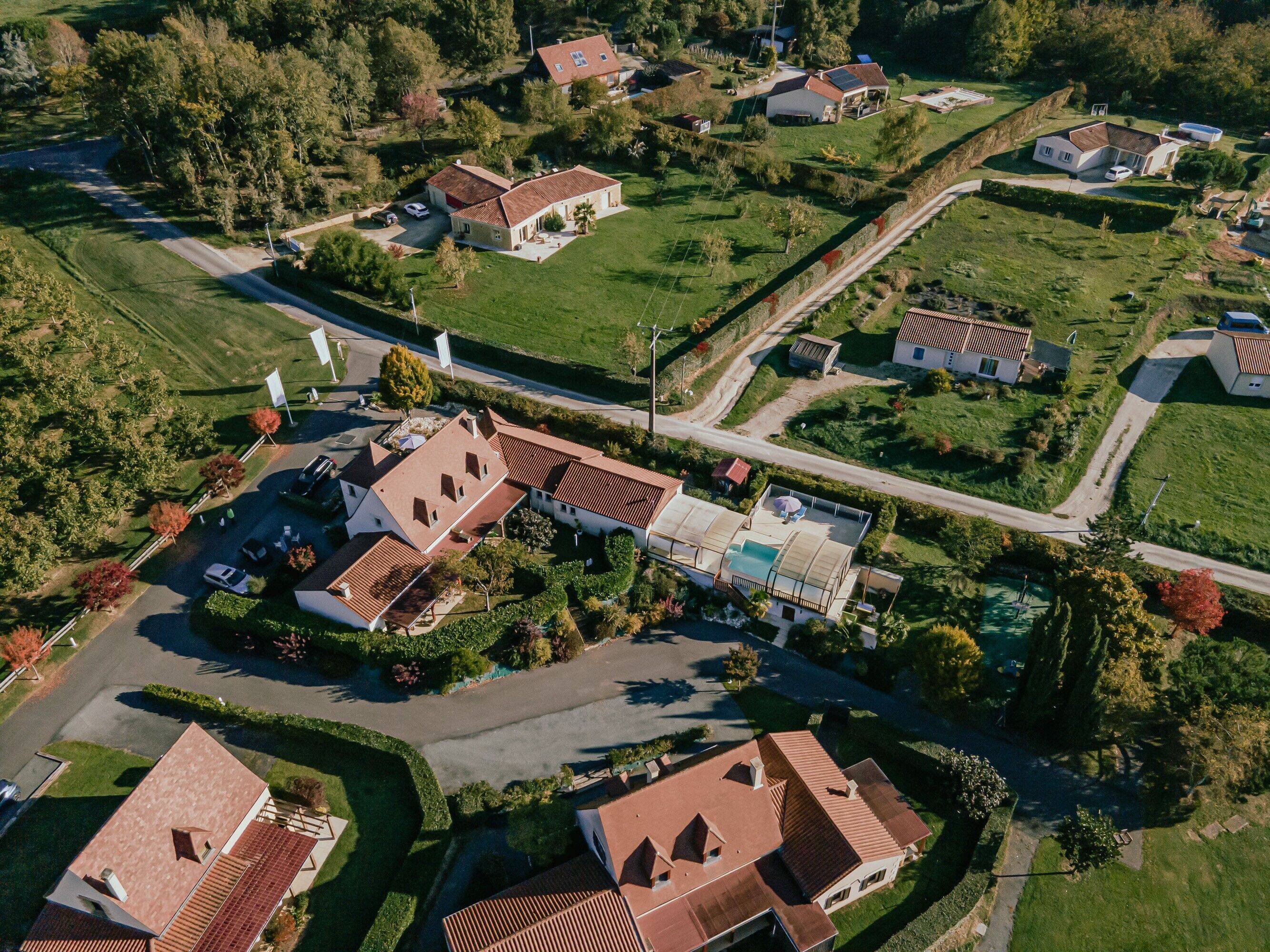 Vue aérienne d’un quartier résidentiel avec des maisons, des rues et une piscine.