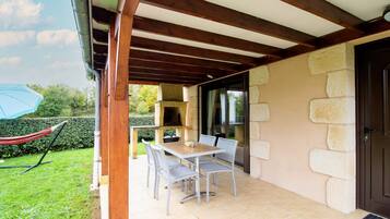 An outdoor patio with a table and chairs, a hammock, and a stone wall.