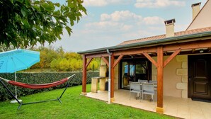 A covered patio area with a table and chairs, a hammock, and a blue umbrella. - Holiday Home 'Maison Tournesol' with Shared Pool, Wi-Fi and Air Conditioning (Castelnaud-la-Chapelle)