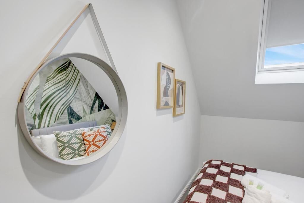 A bedroom with a circular hanging chair, a bed with a checkered blanket, and two framed pictures on the wall.