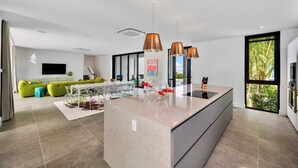A modern kitchen with a central island, pendant lighting, and large windows.