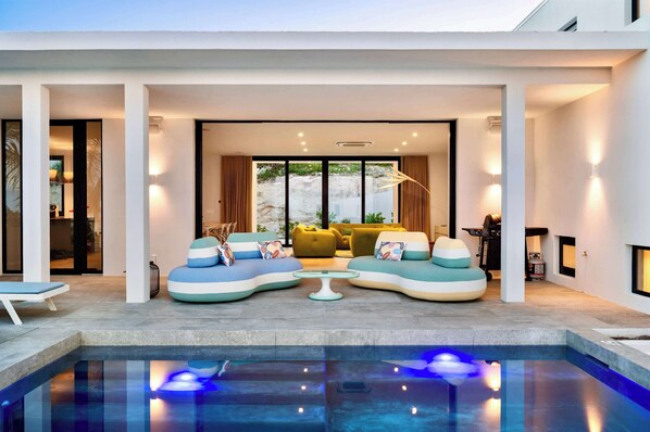 A modern indoor pool area with a seating arrangement and a view of the outdoors. - Villa Jupiter - Oceanview with Private Pool (Providenciales)