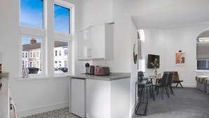 Une cuisine compacte comprenant un réfrigérateur, un petit plan de travail et un coin repas avec des chaises et une table.