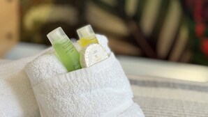 A white towel with two bottles of lotion and a small container of cream. - Stadium View Family & Group 3-bed Retreat (Cardiff)
