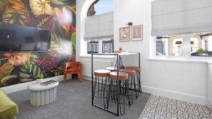 A modern living room with a mural, a TV, a dining table with stools, and a view of the street. - Stadium View Family & Group 3-bed Retreat (Cardiff)