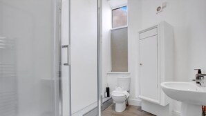 A modern bathroom with a glass shower enclosure, a white toilet, and a sink. - Stadium View Family & Group 3-bed Retreat (Cardiff)