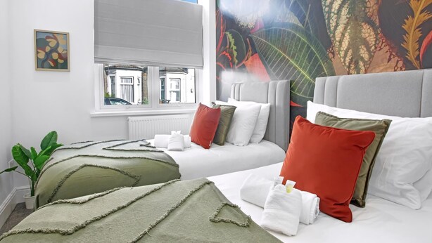 A hotel room with two beds, a large window, a plant, and a mural. - Stadium View Family & Group 3-bed Retreat (Cardiff)