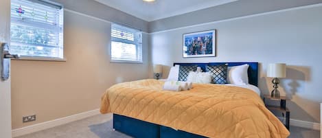 A bedroom with a bed, two bedside tables, a wall-mounted artwork, and a ceiling light fixture.