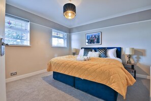 A bedroom with a bed, two bedside tables, a wall-mounted artwork, and a ceiling light fixture. - Spacious Three-bedroom Home With Pool Table (Cardiff)